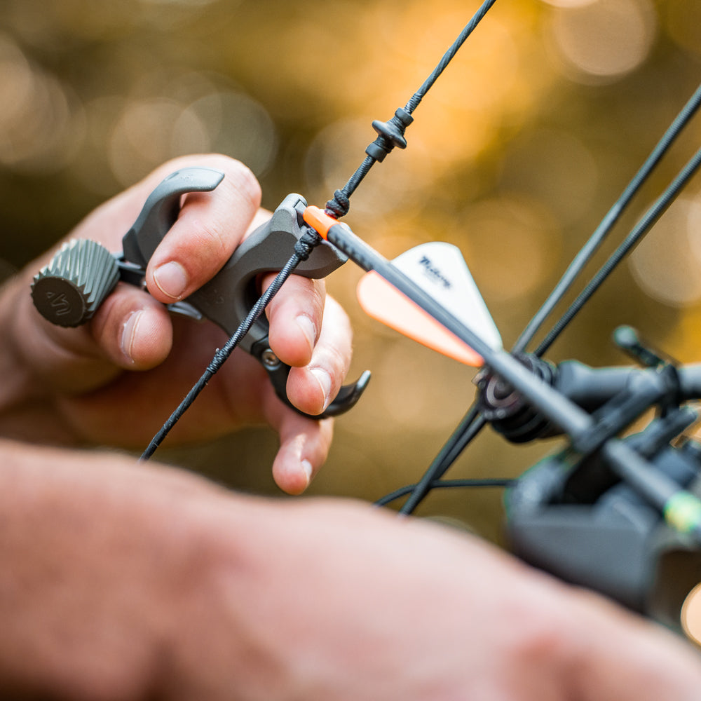 UV BUTTON™ in hand on a bow string