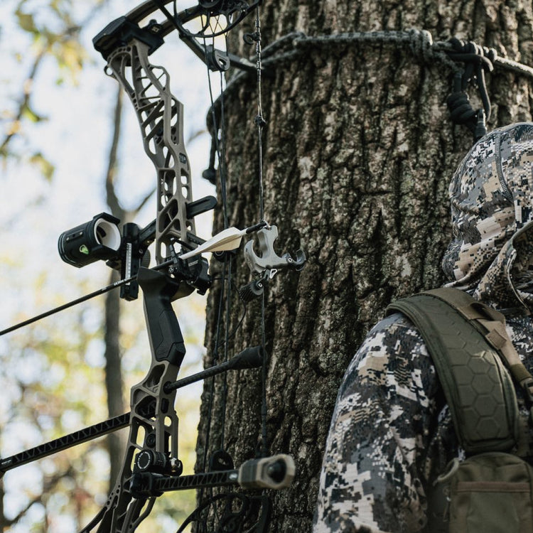 Whitetail hunter in SITKA Optifade Elevated II using a Mathews Lift hanging from a bow hook equipped with the UV Slider™, UV 1K Arrows, UV Button™ in Smoke Gray - Aluminum, and the BEEREAL 2.0 Mathews Grip in Black