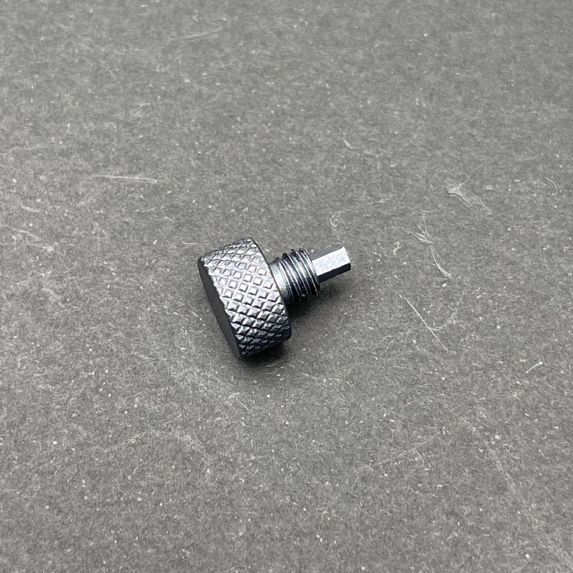 A close-up of the UV Scope Rod Wrench Tool, a small, dark gray metal tool with a textured, knurled cylindrical head and a threaded shaft with a hexagonal end.